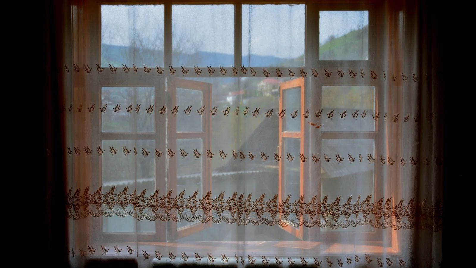 Geöffnetes Fenster mit luftigen Vorhängen an einem warmen Tag
