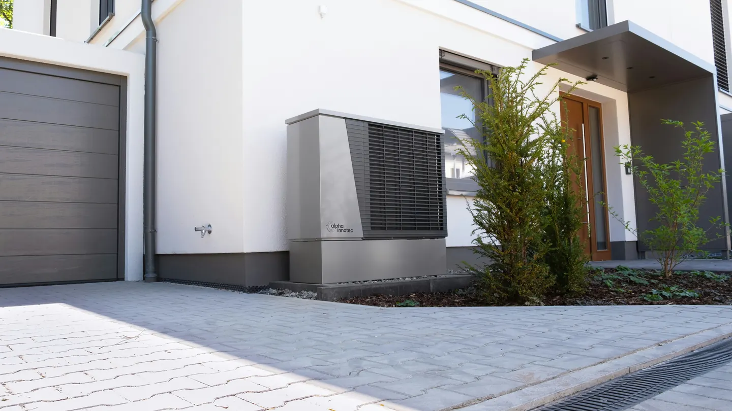 Moderne Luft-Wasser-Wärmepumpe vor einem Wohnhaus